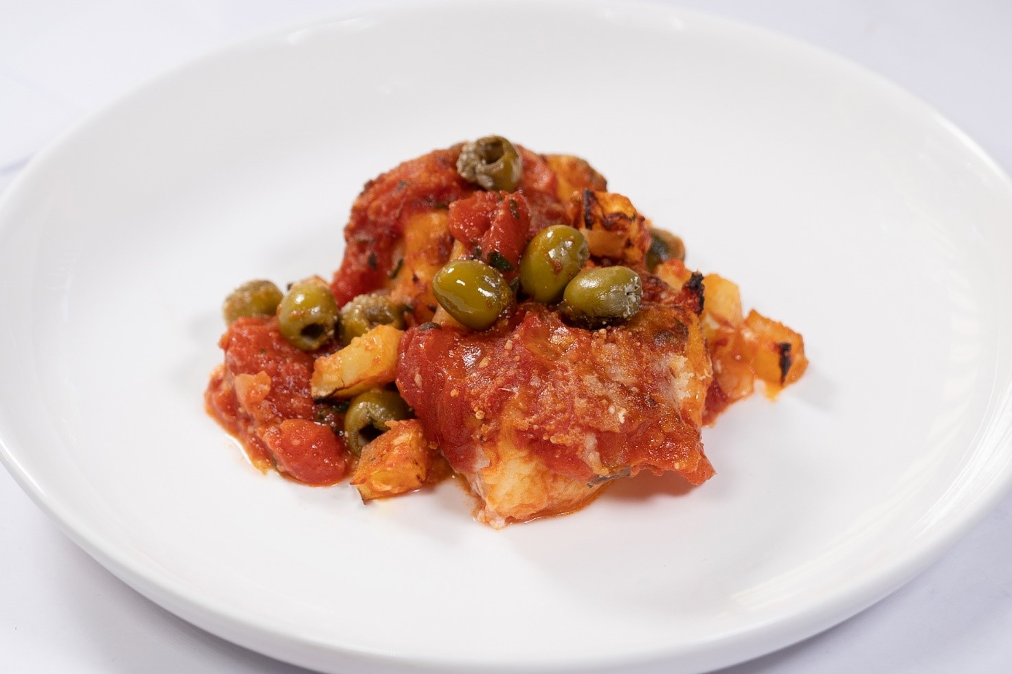 Baked salt cod with potatoes and olives in tomato sauce